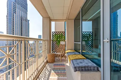 a balcony with a couch and chair on a building at Stylish 1BR with Iconic Burj and Fountain Views, Free Luxury Airport Pick Up Service in Dubai