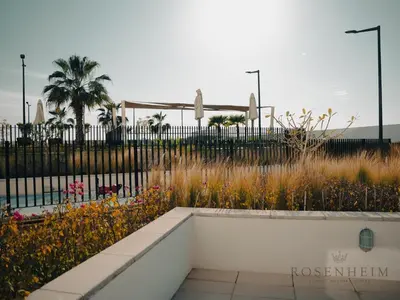 a flower garden with a fence and palm trees at Modern Studio Escape - Pool, Gym & Relaxation in Dubai