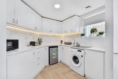 a white kitchen with a washer and dryer in it at Urban Gem 2BR with Stunning Views in Dubai