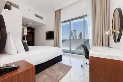 a hotel room with a bed and a desk and a window at Holiday Inn Dubai Jumeirah Village Circle by IHG in Dubai