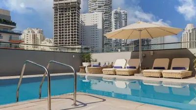 a swimming pool with chairs and an umbrella at Holiday Inn Dubai Jumeirah Village Circle by IHG in Dubai