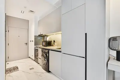 a kitchen with white cabinets and a washer and dryer at Lovely Studio in Mag 900, Meydan in Dubai