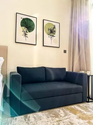 a blue couch in a living room with three pictures at Naseem Elegant Studio Escape in Al Merkadh in Dubai