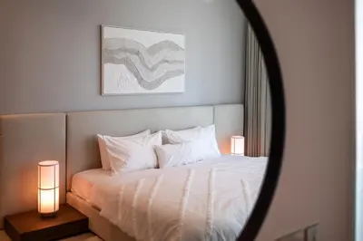 a bedroom with a bed with white pillows and a mirror at Luxury 3BD study in Missoni with private elevator in Dubai