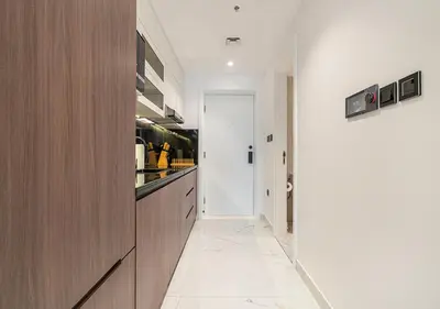 a kitchen with wooden cabinets and a white tile floor at Luxurious Studio with Stunning Burj Khalifa, Pool & Lake Views Steps from Dubai Mall in Dubai