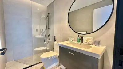 a bathroom with a sink and a toilet and a mirror at 2BR with Extra-Large Balcony Canal & Burj Views by Vibel in Dubai