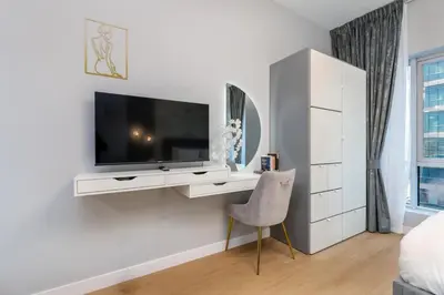 a white room with a tv and a chair at White Sage Stunning New Studio in Marina in Dubai