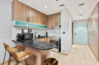 a kitchen with a black counter top and wooden cabinets at Stylish Studio APT with Pool and Gym in Dubai