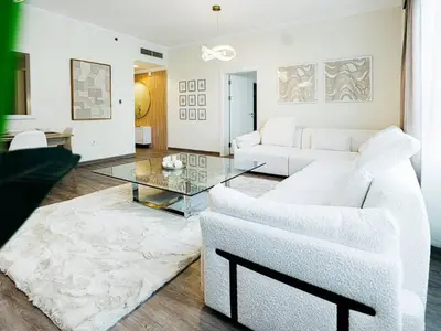 a living room with white furniture and a glass table at DreamShoma- Deluxe 1BR With Lake View in Dubai