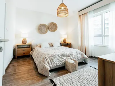 a white bedroom with a bed and two night stands at DreamShoma- Deluxe 1BR With Lake View in Dubai