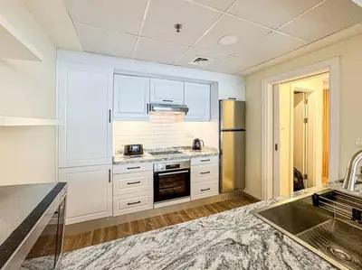 a kitchen with white cabinets and a stove top oven at DreamShoma- Deluxe 1BR With Lake View in Dubai