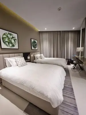 a hotel room with two beds and a desk at 2 Bedroom DAMAC Prive Apartment in Dubai