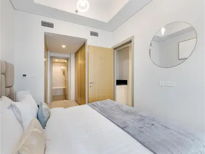 a white bedroom with a large bed and a mirror at ALiving Elegant 2BR plus Maid's Room I Aykon City, Business Bay- 4016 in Dubai