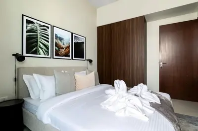 a bedroom with a large white bed with three pictures on the wall at Waves - Canal-View Elegance 1BR Apt in Reva Residences in Dubai