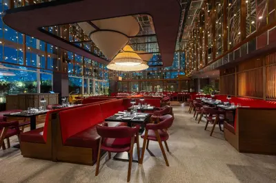 a restaurant with red chairs and tables and windows at Taj Dubai in Dubai