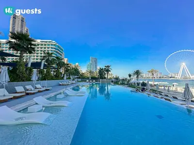 a large swimming pool with chairs and a ferris wheel at HiGuests - Beachside Oasis Stylish 2BR Apartment in La Vie in Dubai