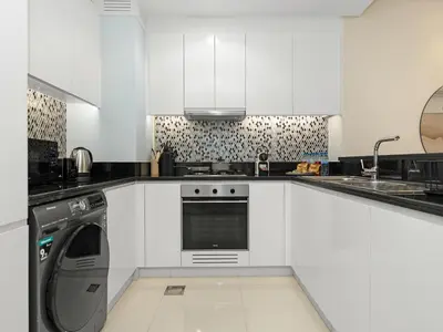 a white kitchen with a washing machine in it at WonderfulStay at Paramount Residences - Highest Infinity Pool - Burj Khalifa View - Brand New Luxury Apartments in Dubai
