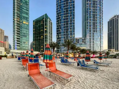 a bunch of chairs and umbrellas on a beach at Artistic Retreat in JBR with Private Beach Access in Dubai