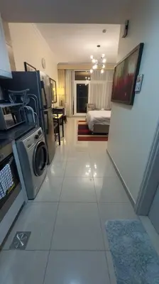 a room with a kitchen and a room with a washing machine at Stylish Studio With Amazing View in Dubai