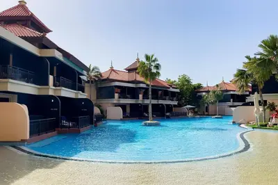 a large swimming pool in a resort with palm trees at Palm Jumeirah Sea View 1Bdr in Dubai