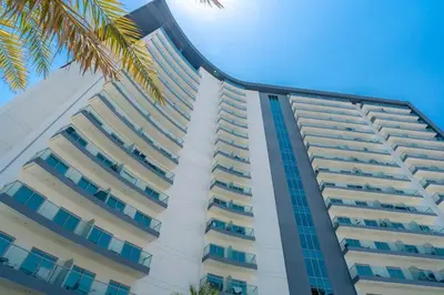 a tall white building with blue windows and a palm tree at Best Place 2B Dubai in Dubai