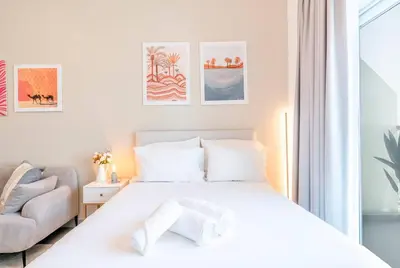 a white bedroom with a bed and a chair at Best Place 2B Dubai in Dubai