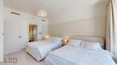 two beds in a bedroom with white sheets and pillows at Luxurious Apartment with Marina Views in Dubai