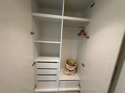 a walk in closet with white walls and white shelves at Your Dubai Home in Dubai
