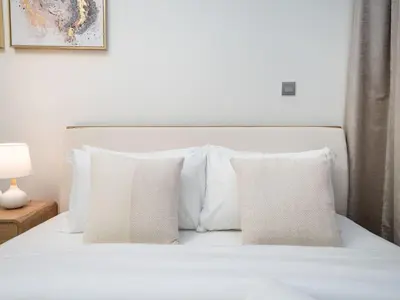 a white bed with white pillows and a picture at Chic Studio Azizi Riviera Retreat with City Views in Dubai