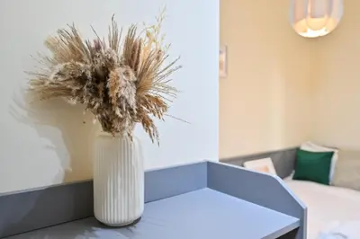 a white vase with a plant sitting on a table at 7 Beds - JBR Beach 3 min walk in Dubai