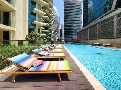 a row of chaise lounge chairs next to a swimming pool at Wonderful New Studio in Missoni Business Bay in Dubai