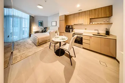 a kitchen and living room with a table and a bed at Wonderful New Studio in Missoni Business Bay in Dubai