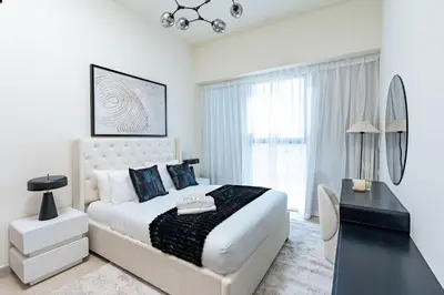a white bedroom with a bed and a desk at Nasma - Modern 3BR Oasis with Balcony in Azizi Riviera in Dubai