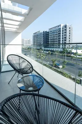 two chairs on a balcony with a view of a city at Nasma - Modern 3BR Oasis with Balcony in Azizi Riviera in Dubai