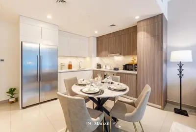 a kitchen with a table and chairs and a refrigerator at Manzil - 2BR Apartment in Palm Jumeirah with Marina View in Dubai