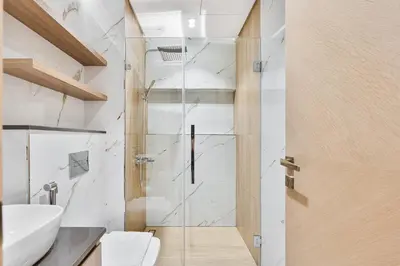 a bathroom with a shower with a glass door at Modern Studio with Pool, Gym and BBQ area in Dubai