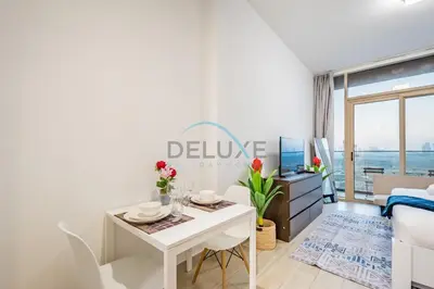a white living room with a table and a couch at Elegant Studio in Bloom Towers B, JVC by Deluxe Holiday Homes in Dubai