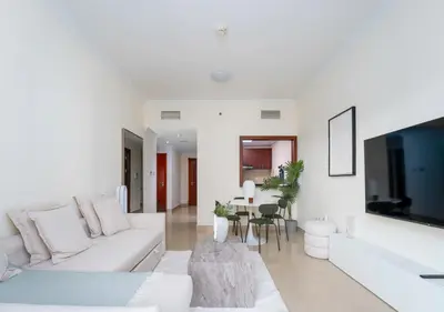 a white living room with a white couch and a tv at Perfect Stay - 1Bedroom with full Marina View in Dubai