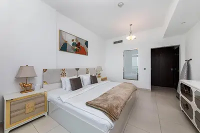 a white bedroom with a large bed and a table at Free Netflix, Sea View, Private Beach & Pool in Dubai