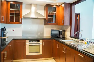 a kitchen with wooden cabinets and a stove top oven at Vserve - 1 BR Spacious Majestic Burj Khalifa view in Dubai