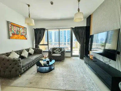 a living room with a couch and a tv at Vserve - 1 BR Spacious Majestic Burj Khalifa view in Dubai