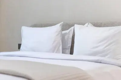 a white bed with white pillows on it at Premium 1BR Haven with Burj Khalifa, City Skyline Views, Pool, Gym & Balcony in Dubai