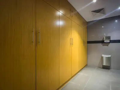 a locker room with yellow cabinets and a trash can at Chic Studio Stay with Gym, Pool, and Kitchenette in Dubai