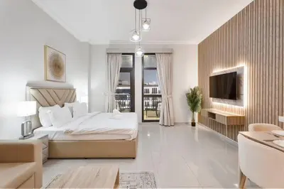 a white bedroom with a bed and a tv at Chic Studio Stay with Gym, Pool, and Kitchenette in Dubai