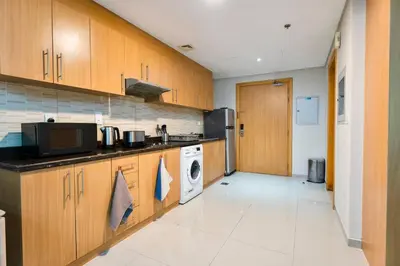 a kitchen with wooden cabinets and a washer and dryer at Chic Studio Stay with Gym, Pool, and Kitchenette in Dubai