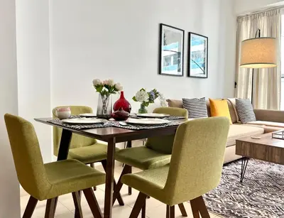 a dining room table with green chairs in a living room at Modern 1BR Unit with Canal View Near Burj Khalifa in Dubai