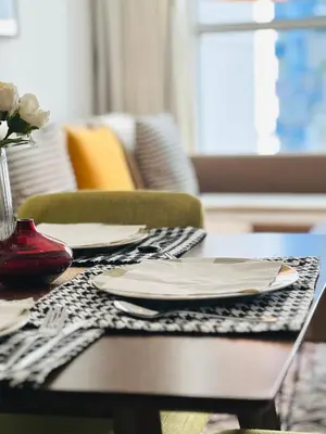 a table with plates and a vase of flowers on it at Modern 1BR Unit with Canal View Near Burj Khalifa in Dubai