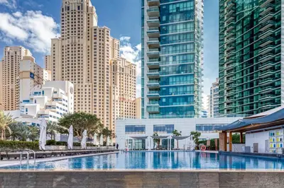 a large swimming pool in a city with tall buildings at Beachy Getaway in JBR with Private Beach Access in Dubai