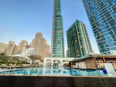 a large swimming pool in a city with tall buildings at Beachy Getaway in JBR with Private Beach Access in Dubai