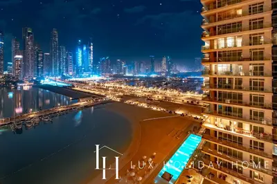 a city at night with a beach and buildings at LUX The Marina Vista Beachfront Suite 4 in Dubai